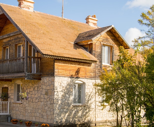 La facciata di una casa in pietra a due piani con un attico e un tetto di tegole marroni.