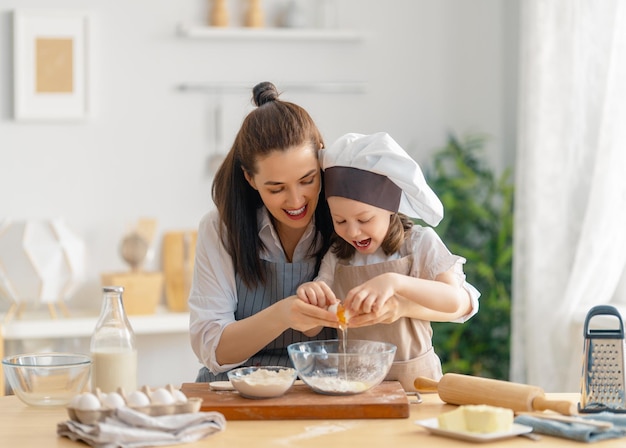 La famiglia amorevole felice sta preparando la panetteria insieme Madre e figlia bambina cucinano biscotti e si divertono in cucina Cibo fatto in casa e piccolo aiutante