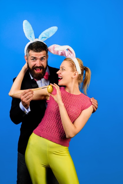 La famiglia celebra le feste felici delle coppie del coniglietto di pasqua donna felice che dipinge l'uovo di pasqua della famiglia di pasqua