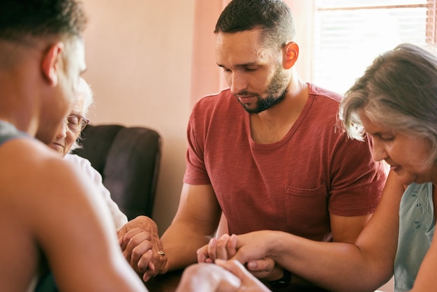 La famiglia che prega insieme resta unita Inquadratura di una famiglia che si tiene per mano con gli occhi chiusi in preghiera