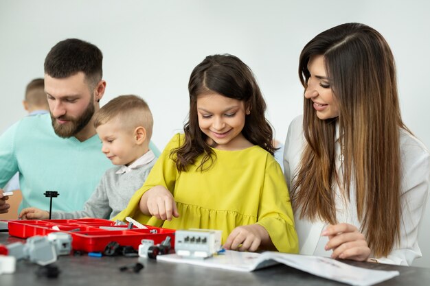 La famiglia con bambini in un club di robotica realizza un robot controllato da un costruttore.