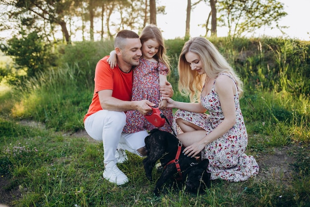 La famiglia con la figlia e il cane giocano insieme in giardino in estate