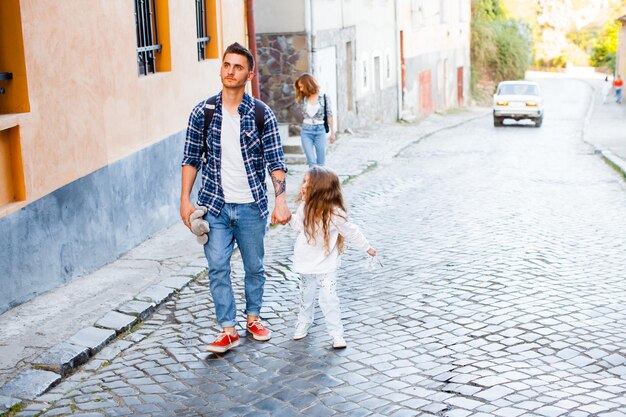 La famiglia di turisti di quattro persone sale per la strada del centro storico L'uomo, la donna e due bambine passeggiano per una città europea