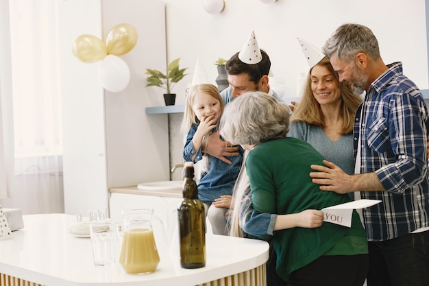 La famiglia e le loro due figlie festeggiano il compleanno della nonna Bambina che abbraccia sua nonna