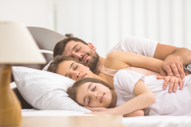 La famiglia felice che dorme sul letto