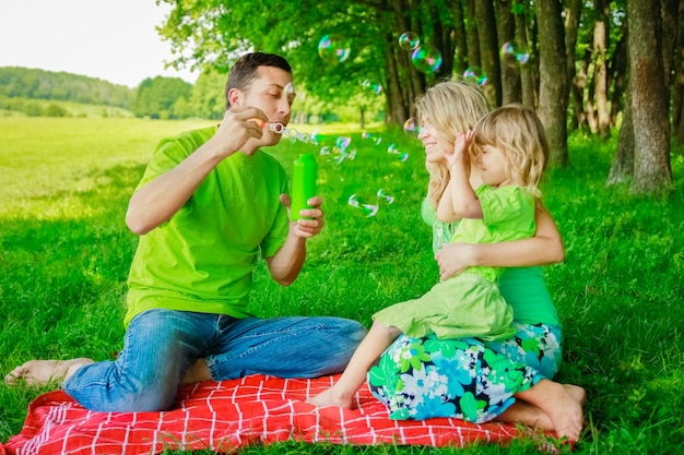 La famiglia felice che fa le bolle nel parco naturale