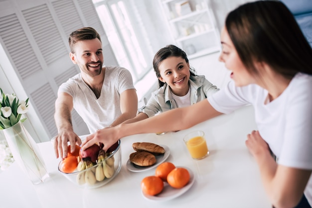 La famiglia felice che prende le mele sul tavolo