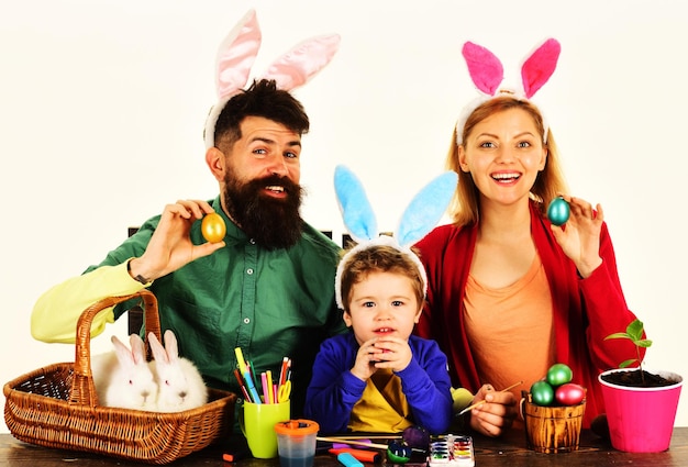 La famiglia felice che si prepara per la madre di pasqua padre e figlio con uova dipinte colorate si siedono a tavola