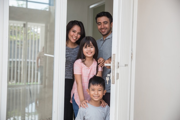 La famiglia felice con i bambini apre la porta di casa