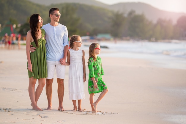 La famiglia felice con i bambini cammina sulla spiaggia