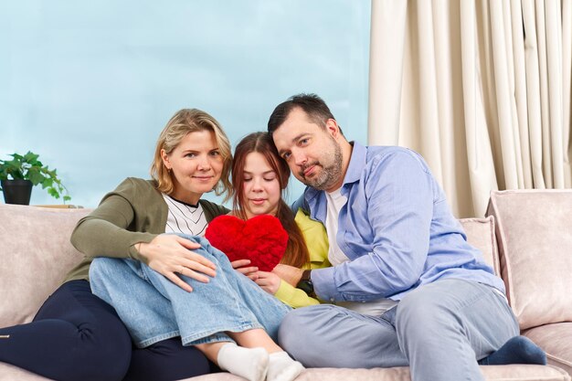 La famiglia felice con i bambini si siede sul divano nel soggiorno e si diverte I genitori sorridenti riposano sul divano e si godono il fine settimana