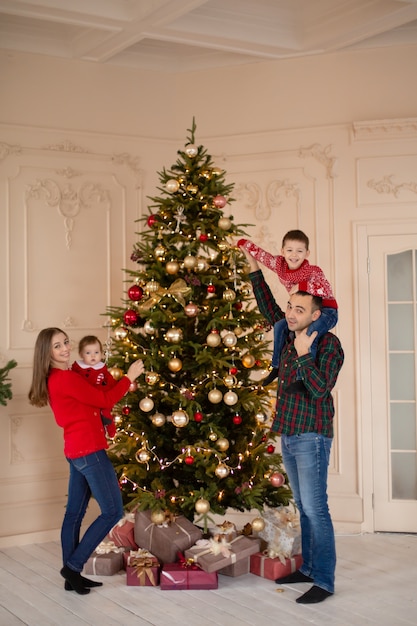 La famiglia felice decora insieme l'albero di Natale al chiuso