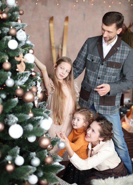 La famiglia felice decora l'albero di Natale nel loro salotto.