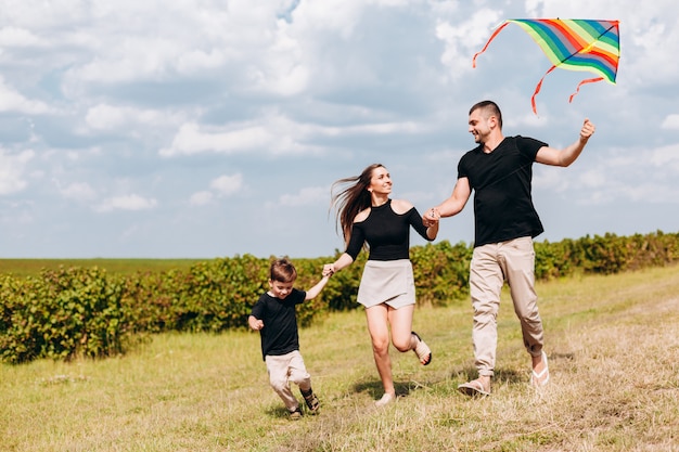 La famiglia felice del primo piano lancia un aquilone sulla natura.