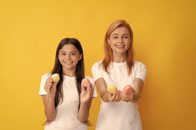 La famiglia felice della donna e della ragazza teenager tiene i biscotti francesi del macaron maccherone francese