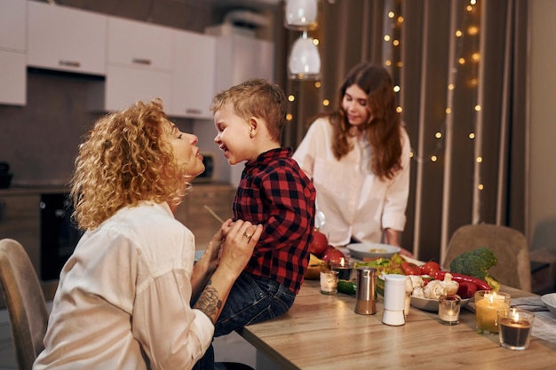 La famiglia felice di madre figlia e figlio è in cucina la sera