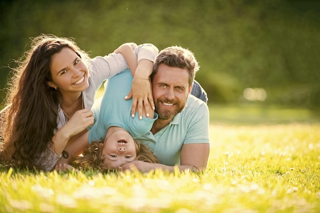 La famiglia felice di mamma, padre e figlio, si rilassa nella famiglia dell'erba verde del parco estivo