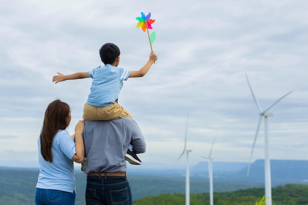 La famiglia felice e progressista si diverte al parco eolico per il concetto di energia verde