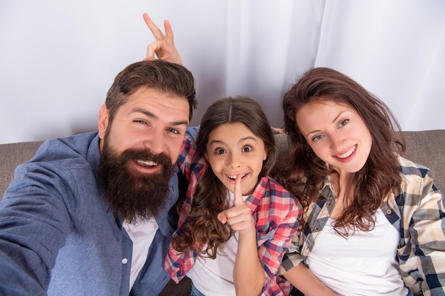 La famiglia felice fa selfie seduto sul divano nel fine settimana della famiglia a casa