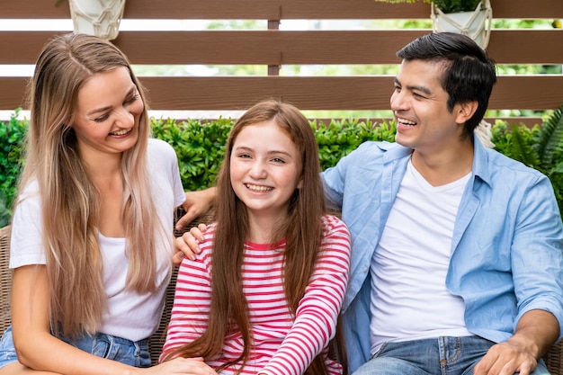 La famiglia felice seduta sul divano da giardino godetevi il tempo di qualità e lo stare insieme Concetto di relazione familiare