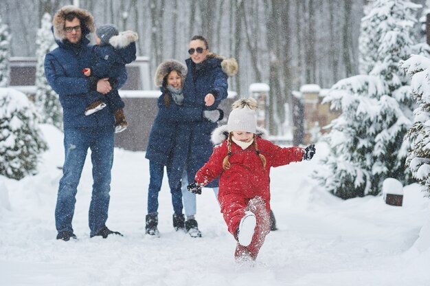 La famiglia felice si diverte fuori vicino alla casa in inverno