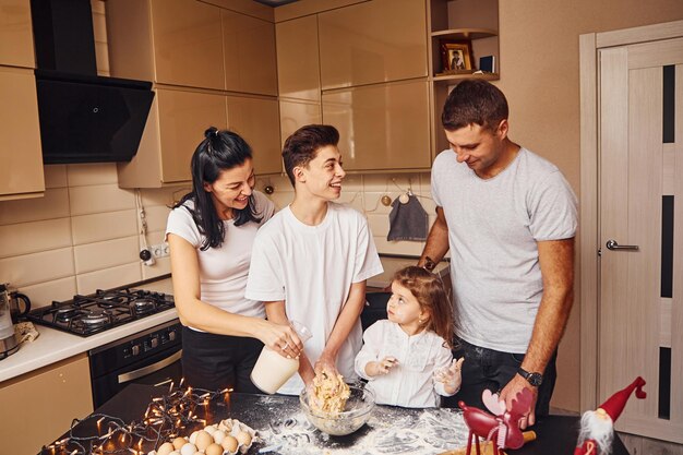 La famiglia felice si diverte in cucina e a preparare il cibo.