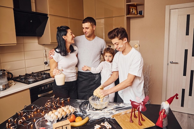 La famiglia felice si diverte in cucina e a preparare il cibo.