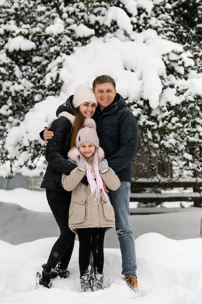 La famiglia felice si diverte nella foresta invernale. Madre, padre e figlia che giocano con la neve. Divertirsi a passare del tempo insieme. concetto di famiglia