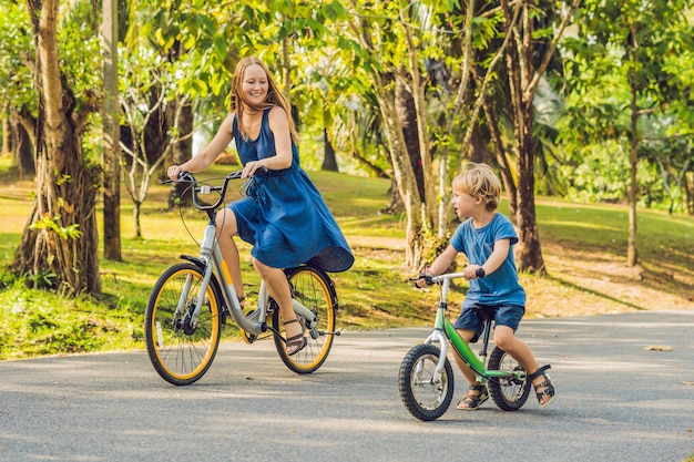 La famiglia felice sta andando in bicicletta all'aperto e sorride. Mamma in bici e figlio in cyclette