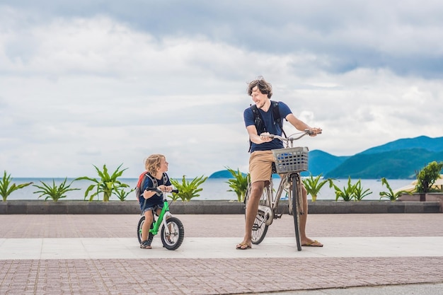 La famiglia felice sta andando in bicicletta all'aperto e sorride. Padre in bicicletta e figlio in bicicletta.