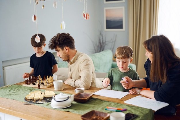 La famiglia felice trascorre del tempo insieme a casa, il padre gioca a scacchi con il figlio, la madre che disegna con il bambino a casa
