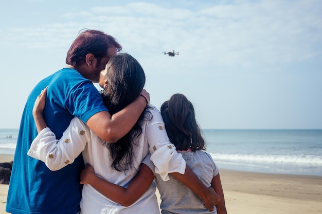 La famiglia indiana felice sta azionando il drone tramite telecomando nella spiaggia di Goa
