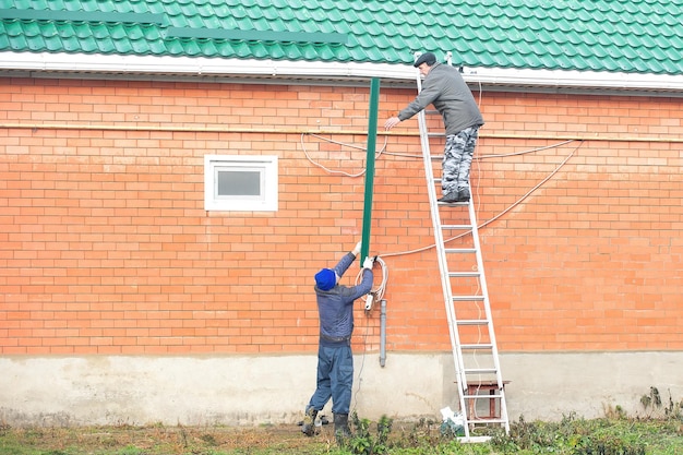 la famiglia prepara la casa per l'inverno, gli uomini installano paraneve sul tetto della casa
