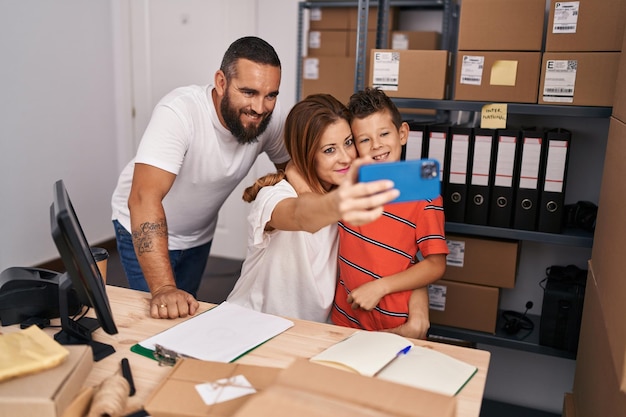 La famiglia sorridente sicura fa il selfie dallo smartphone che lavora al magazzino