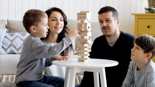 La famiglia sta giocando con una torre di legno a casa