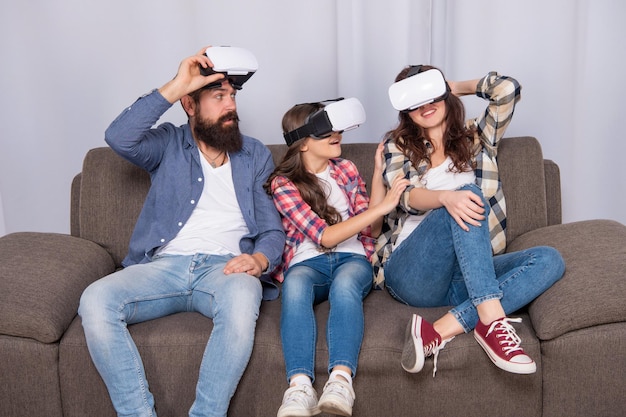 La famiglia stupita indossa occhiali vr seduti sul divano di casa, videogiochi.