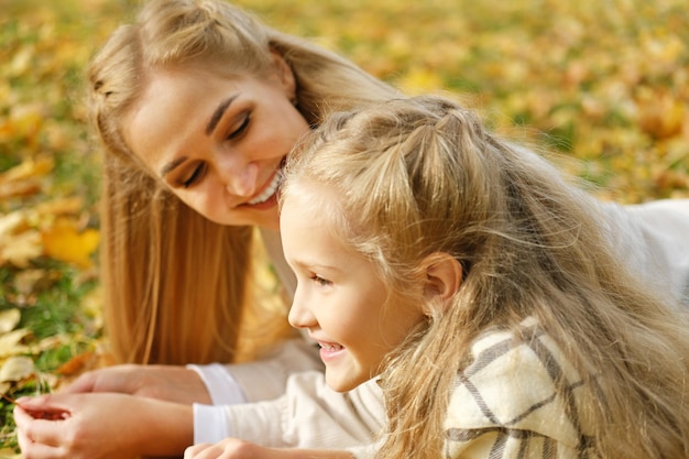 La famiglia trascorre del tempo insieme nel parco Ragazza e madre giacciono su una coperta e parlano Foto orizzontale