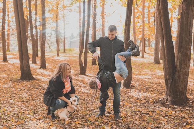 La famiglia trascorre del tempo nel parco autunnale con un cane. Padre, madre e figlia e jack russell terrier cane si divertono in autunno