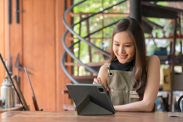 La felicità del progettista creativo adulto femminile asiatico pensa al lavoro e alla ricerca e prendi nota di idee interessanti tramite il dispositivo tabletdonna asiatica che lavora casualmente si rilassa nel suo studio di casa con emozione positiva