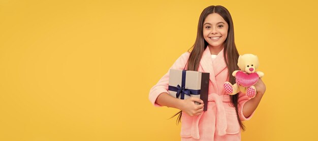 La felicità dell'infanzia buongiorno bambino indossa una morbida tuta da notte gioca con un bambino giocattolo in un comodo pigiameria Ragazza adolescente con poster orizzontale regalo di compleanno Intestazione banner con spazio per la copia