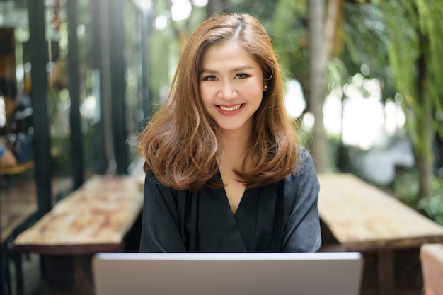 La femmina asiatica astuta sta lavorando con il computer portatile