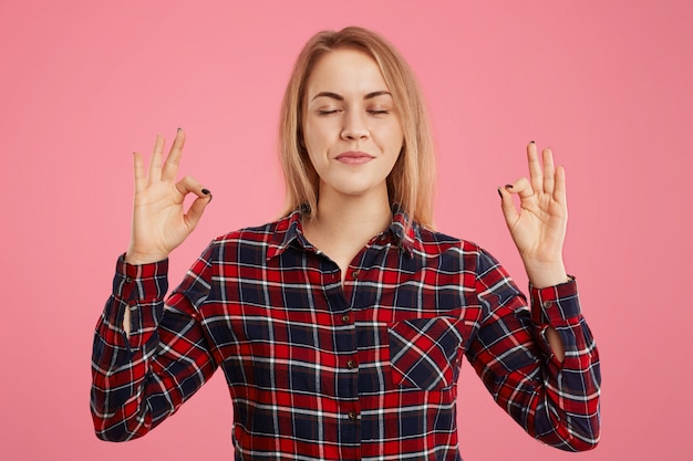 La femmina concentrata positiva tiene le mani nel gesto di mudra