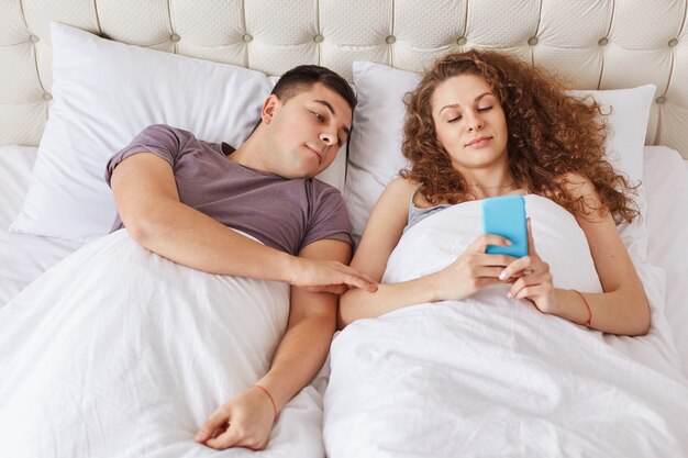 La femmina dipendente si trova a letto con lo Smart Phone