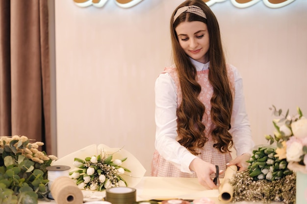 La femmina fa i giardinieri del mazzo di primavera nel negozio di fiori rendono il negozio di fiori di stile di vita del mazzo bello