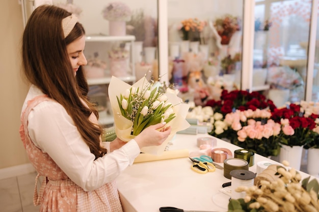 La femmina fa i giardinieri del mazzo di primavera nel negozio di fiori rendono il negozio di fiori di stile di vita del mazzo bello