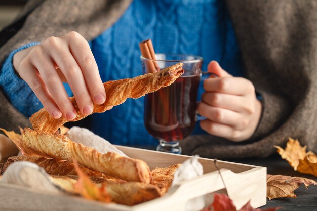 La femmina in coperta accogliente mangia i biscotti sulla tavola