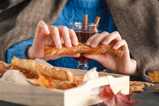 La femmina in coperta accogliente mangia i biscotti sulla tavola