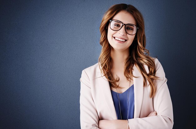 La fiducia crea il successo che merito Ritratto in studio di una giovane donna d'affari attraente e sicura di sé in posa su uno sfondo blu scuro