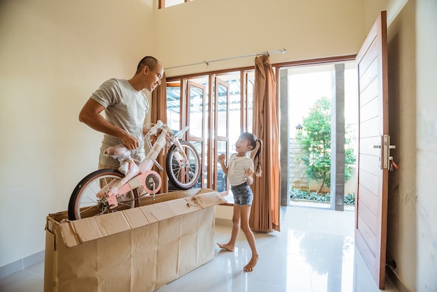 La figlia balla felice quando suo padre disimballa una mini bici