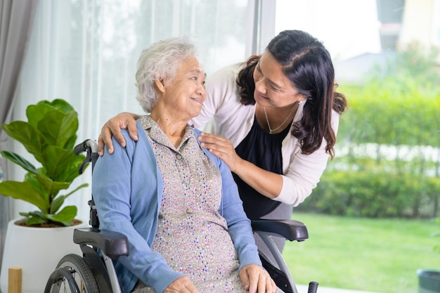 La figlia del caregiver aiuta una donna anziana asiatica anziana o anziana seduta su una sedia a rotelle.